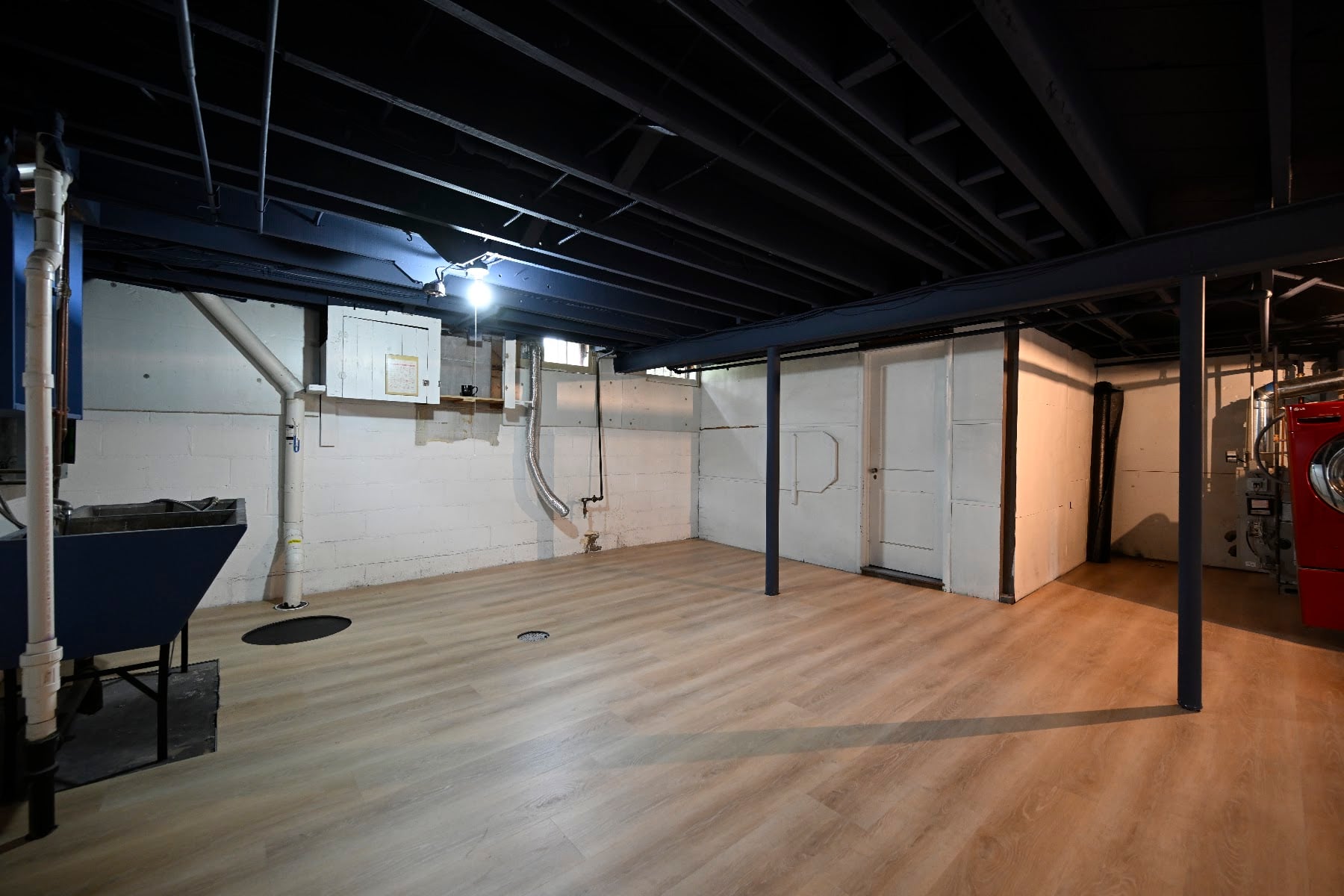 Basement storage rooms with white doors, painted block walls and new plank flooring running to the threshold