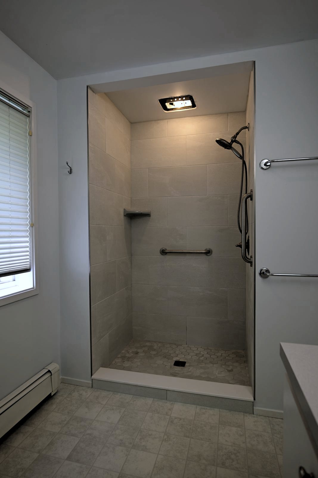 Finished walk-in shower beside a window with new sheet vinyl flooring in an Ann Arbor bathroom