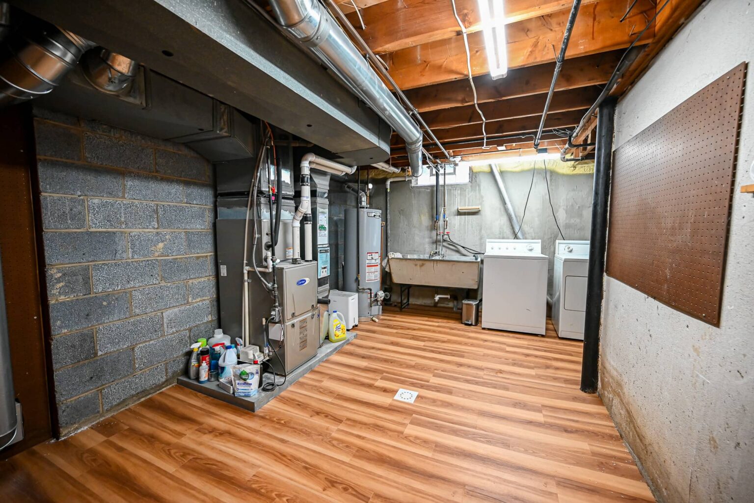Basement utility side with new vinyl plank flooring, painted block walls and open joists