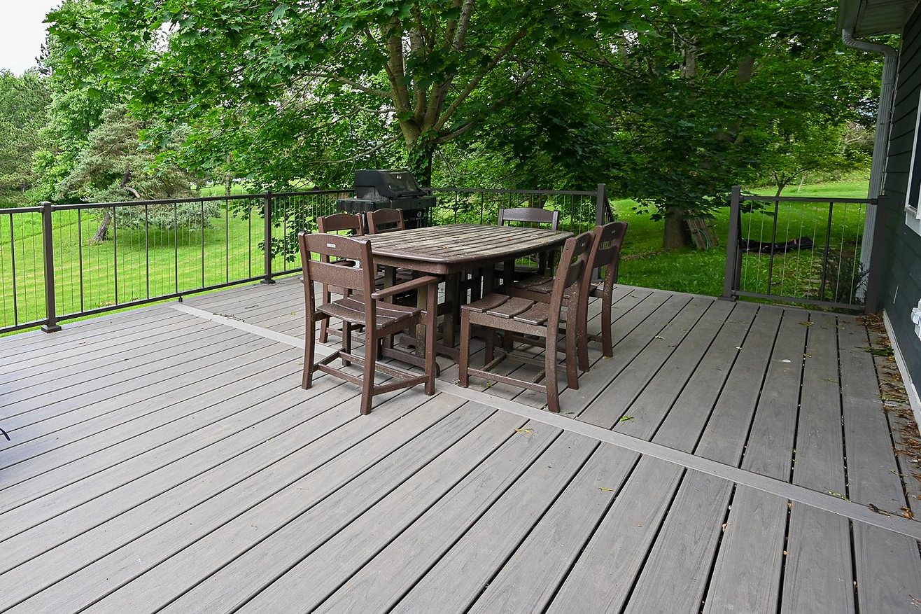Rebuilt back deck with gray composite boards in a bordered layout and a black metal railing with vertical balusters