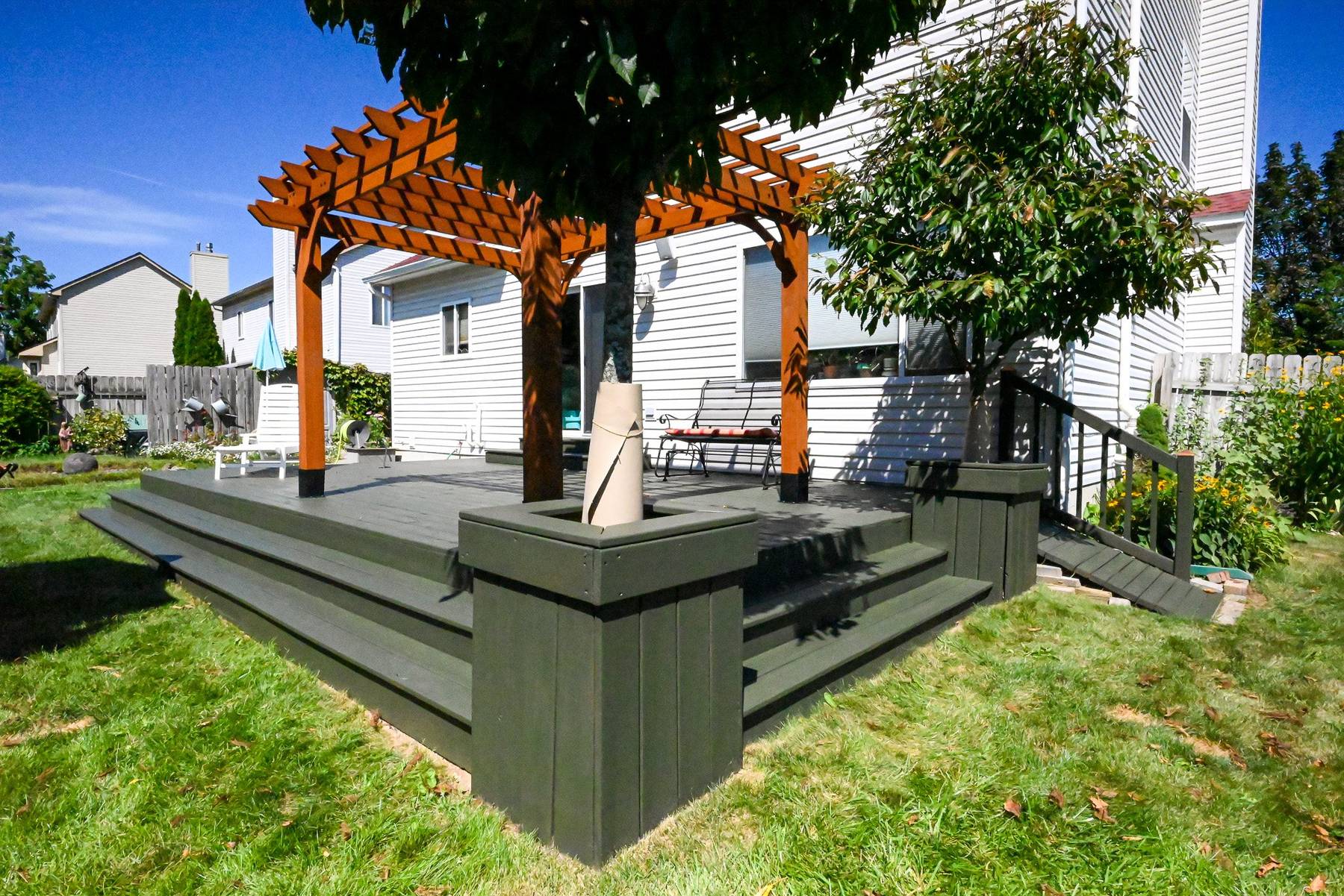 Corner of the refinished deck showing the cedar pergola posts, planter box and restained wraparound steps