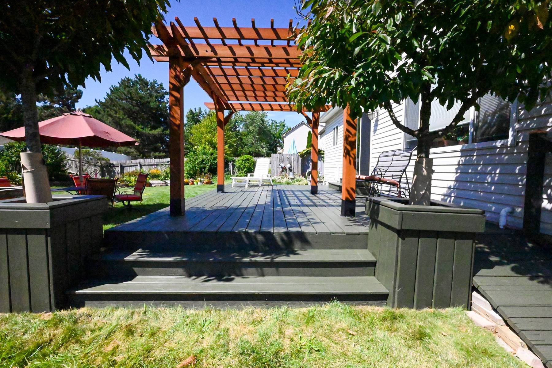 Refinished Ann Arbor deck with built-in planter boxes, a stained cedar pergola and wide steps down to the lawn