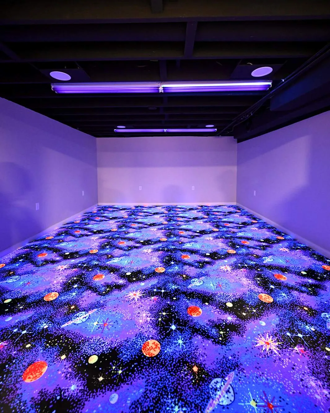 Finished basement rec room in a Canton home with glow-in-the-dark galaxy carpet under blacklight fixtures and a black painted open ceiling