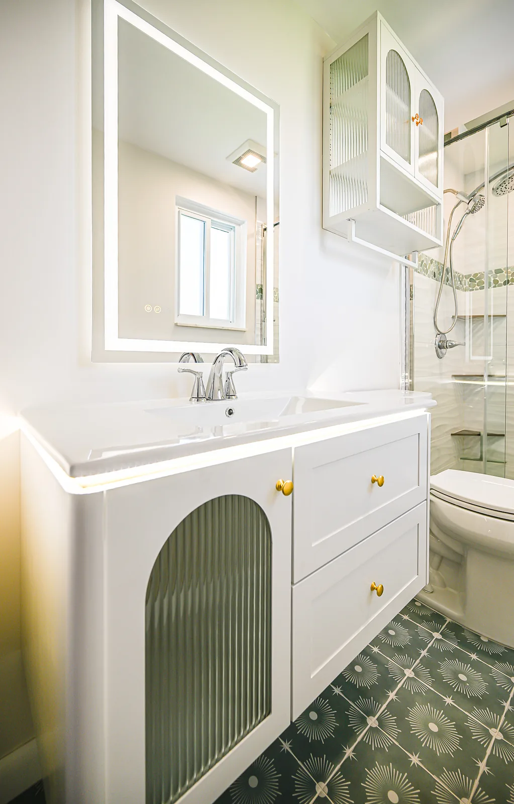 White floating vanity with a fluted arched door, brass knobs, under-cabinet LED glow and a lighted mirror