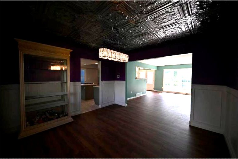 Dining room under a pressed-tin ceiling with the open kitchen and island beyond in the Canton whole home remodel