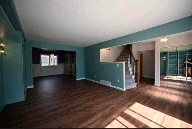 Open teal great room in the Canton whole home remodel with new dark hardwood, a staircase and the kitchen beyond