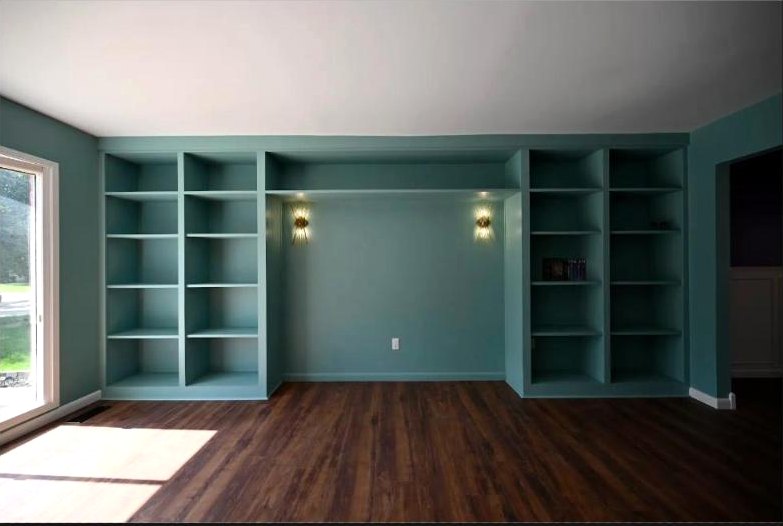 A full wall of custom teal built-in shelving with brass sconces in the Canton whole home remodel