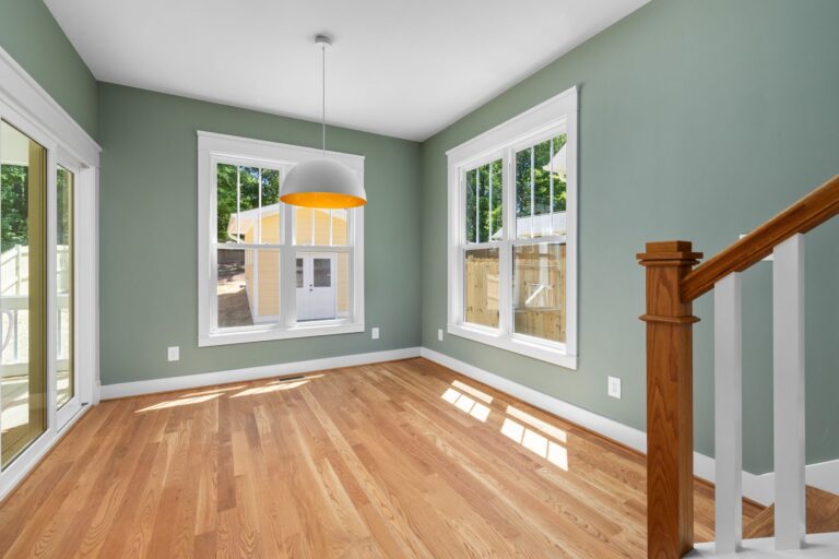 Empty room with freshly finished walls, white trim and a hardwood floor