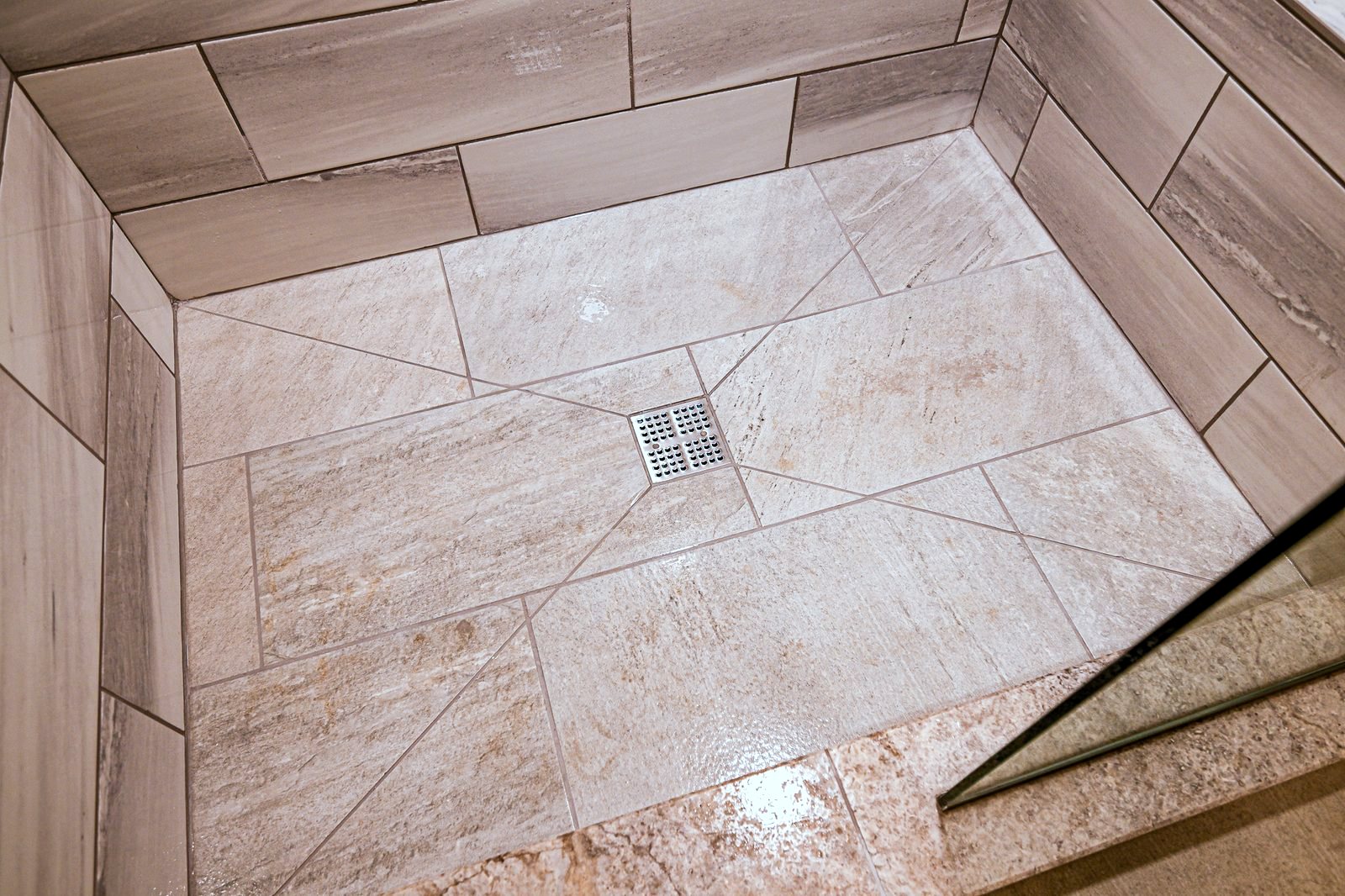 Diagonal-set shower floor tile sloped to a square center drain in a Plymouth walk-in shower