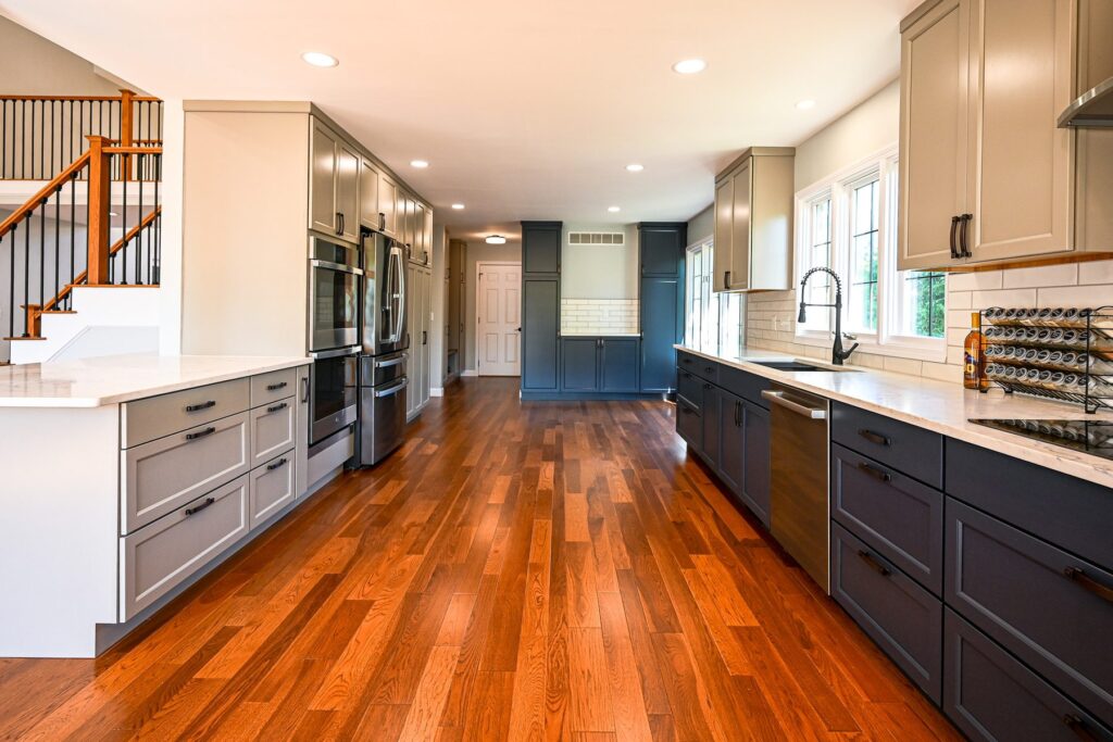 Kitchen after, with two-tone cabinets, white counters, a subway tile backsplash and new hardwood