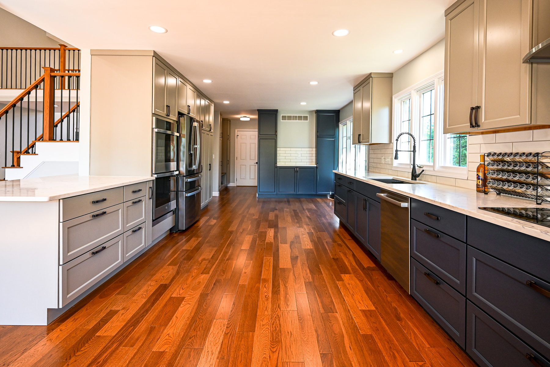 Remodeled kitchen with two-tone cabinets, white counters, subway tile backsplash and new hardwood flooring