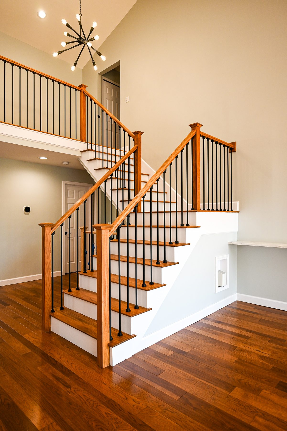 New oak staircase railing with black metal balusters and hardwood treads after the remodel