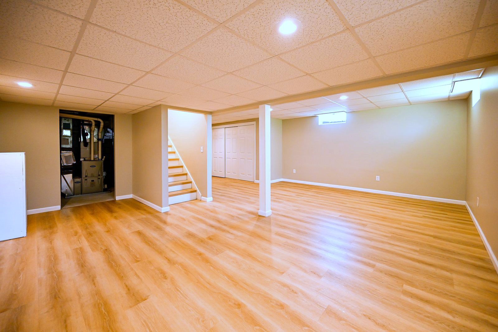 Wide view of the refinished Ypsilanti basement showing the stairs and tucked-away mechanical closet