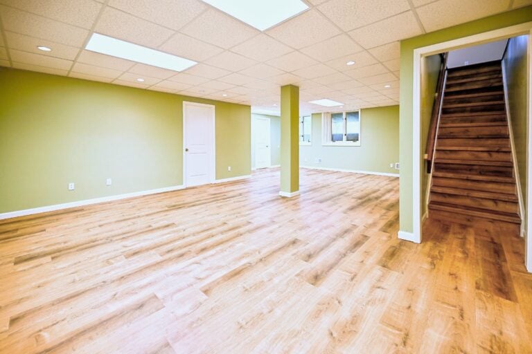 Finished basement rec room in Ann Arbor with sage green walls and wide plank luxury vinyl flooring