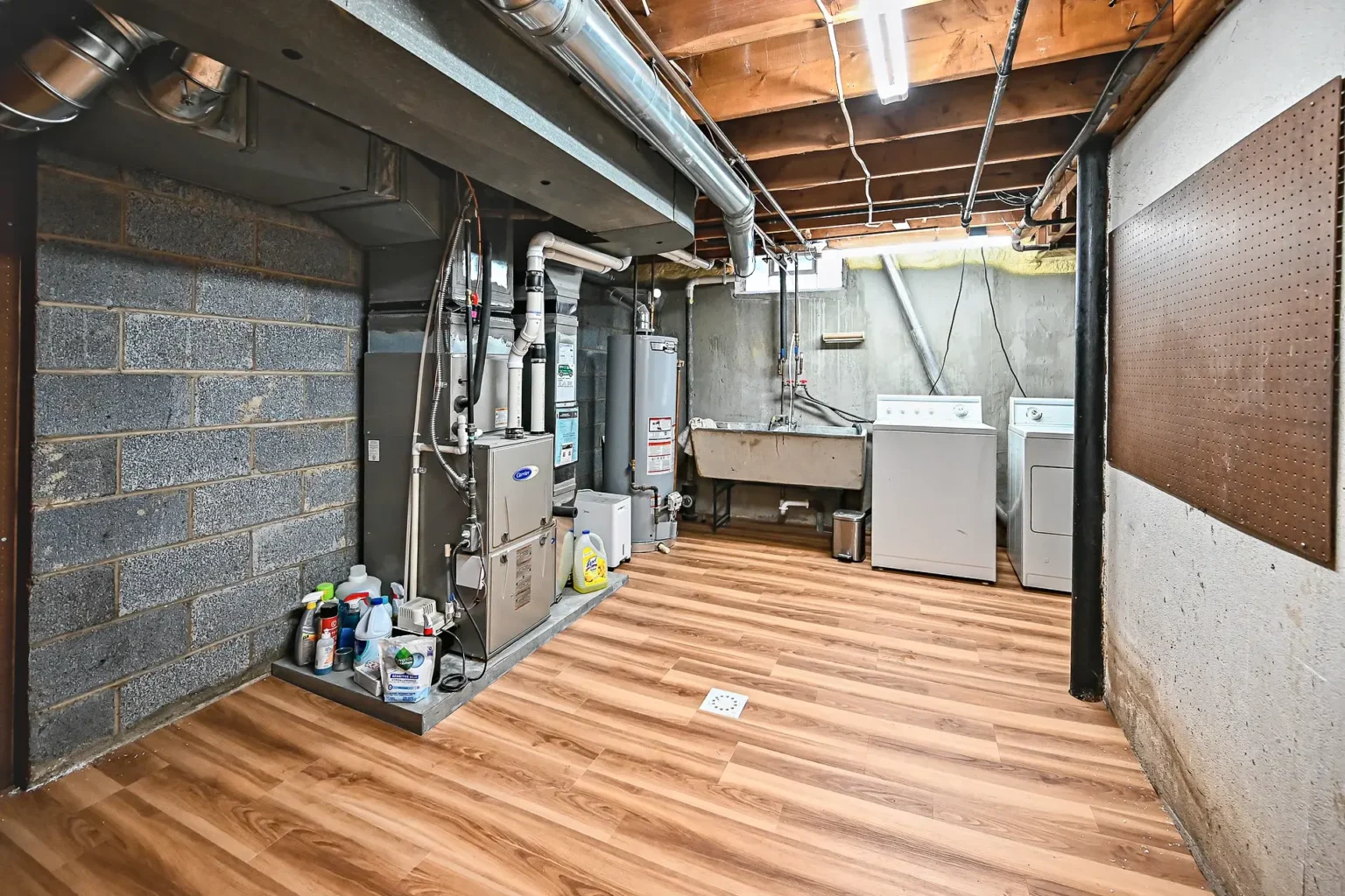 Basement utility side with new vinyl plank flooring, painted block walls and open joists