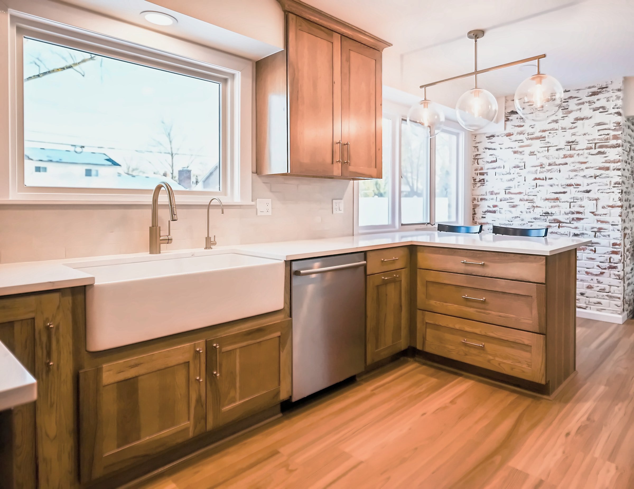 Remodeled Ann Arbor kitchen with a white farmhouse sink under a picture window, quartz counters and a wood-look floor