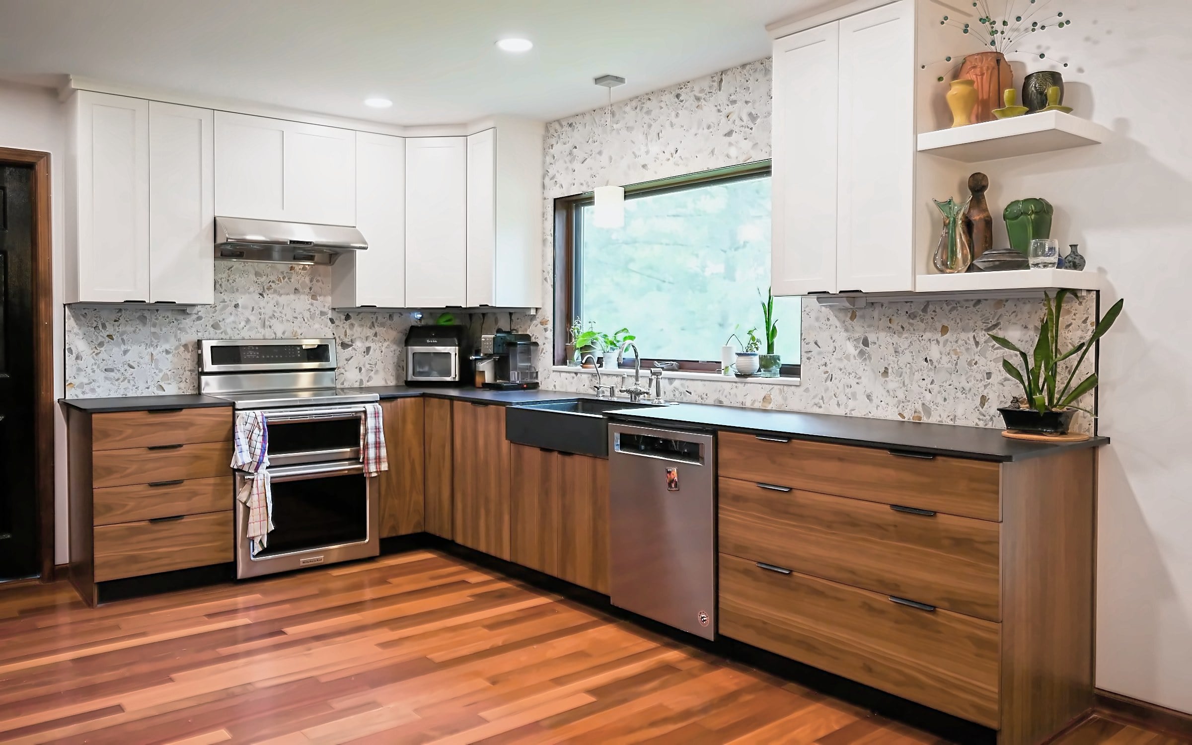 Remodeled Ann Arbor kitchen with walnut slab base cabinets, white shaker wall cabinets, a terrazzo backsplash and matte black counters