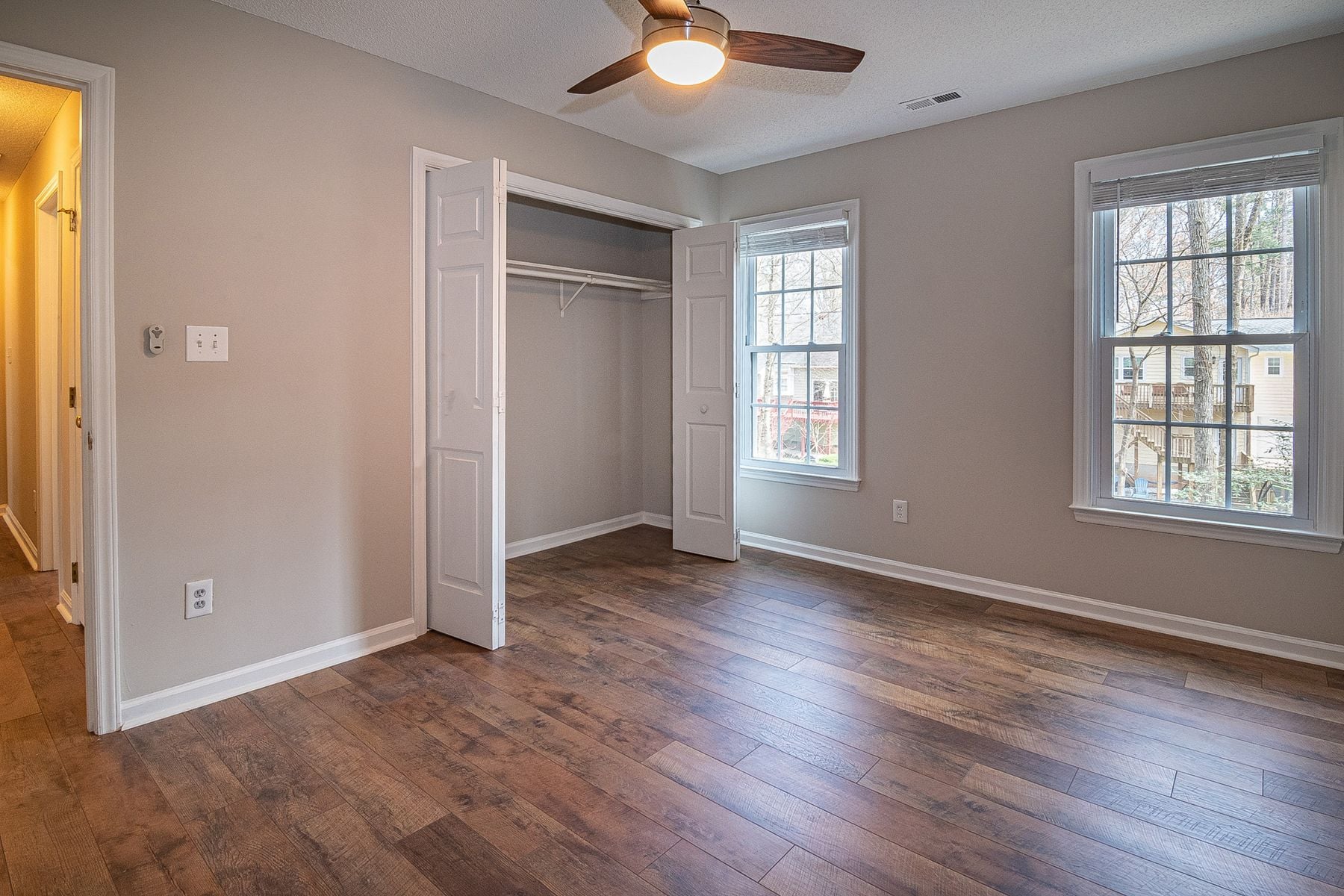 Freshly painted empty apartment bedroom with vinyl plank flooring, a closet and double-hung windows