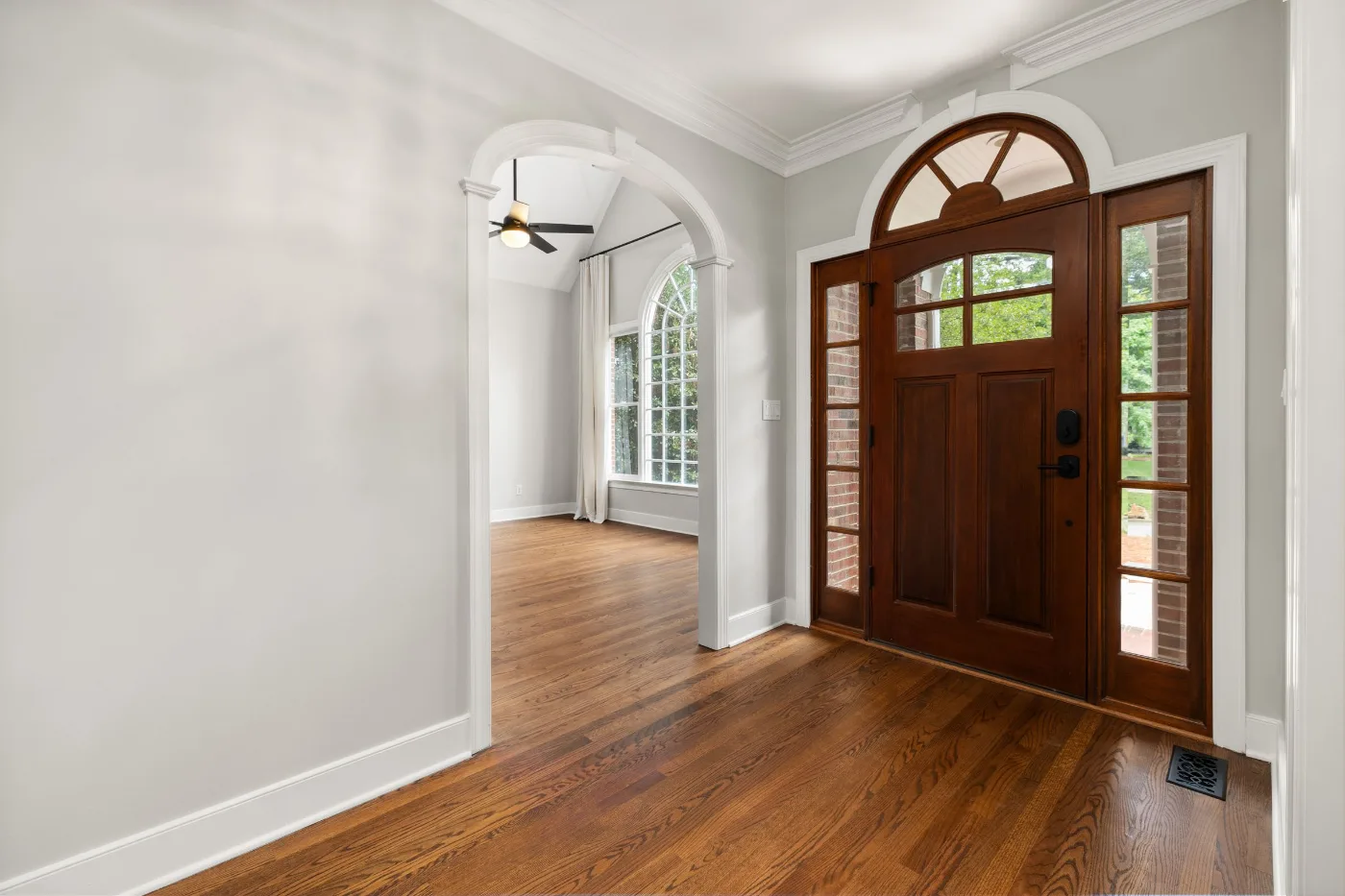 Foyer with an arched wood front door, sidelights and hardwood floors