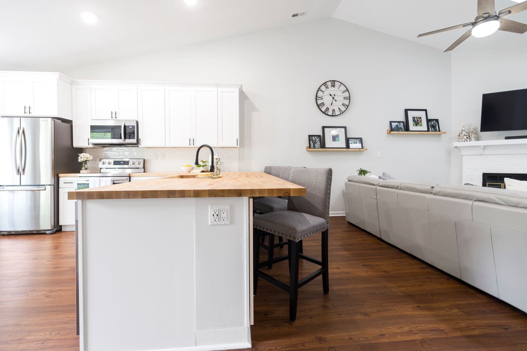 Butcher block island with a gray stool, open to a living room with a sectional sofa