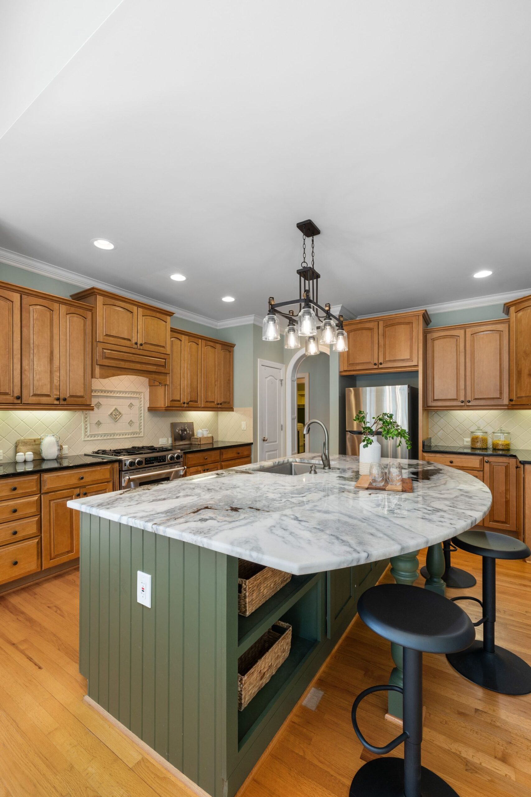 Heavily veined granite island with a prep sink in a kitchen with honey oak cabinets