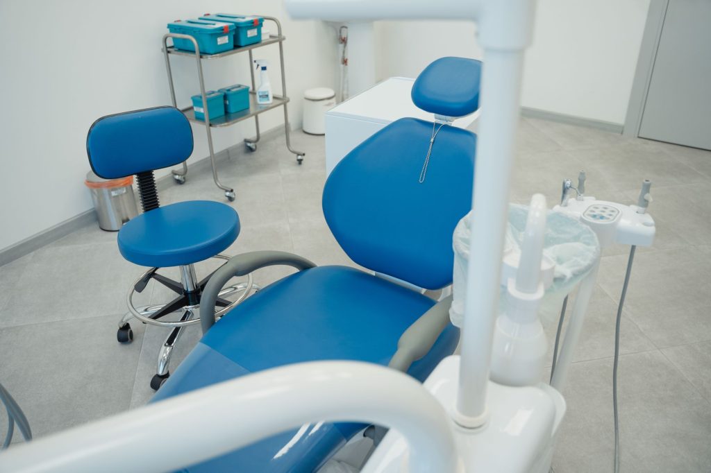 Dental operatory with a blue patient chair, delivery unit and white cabinets