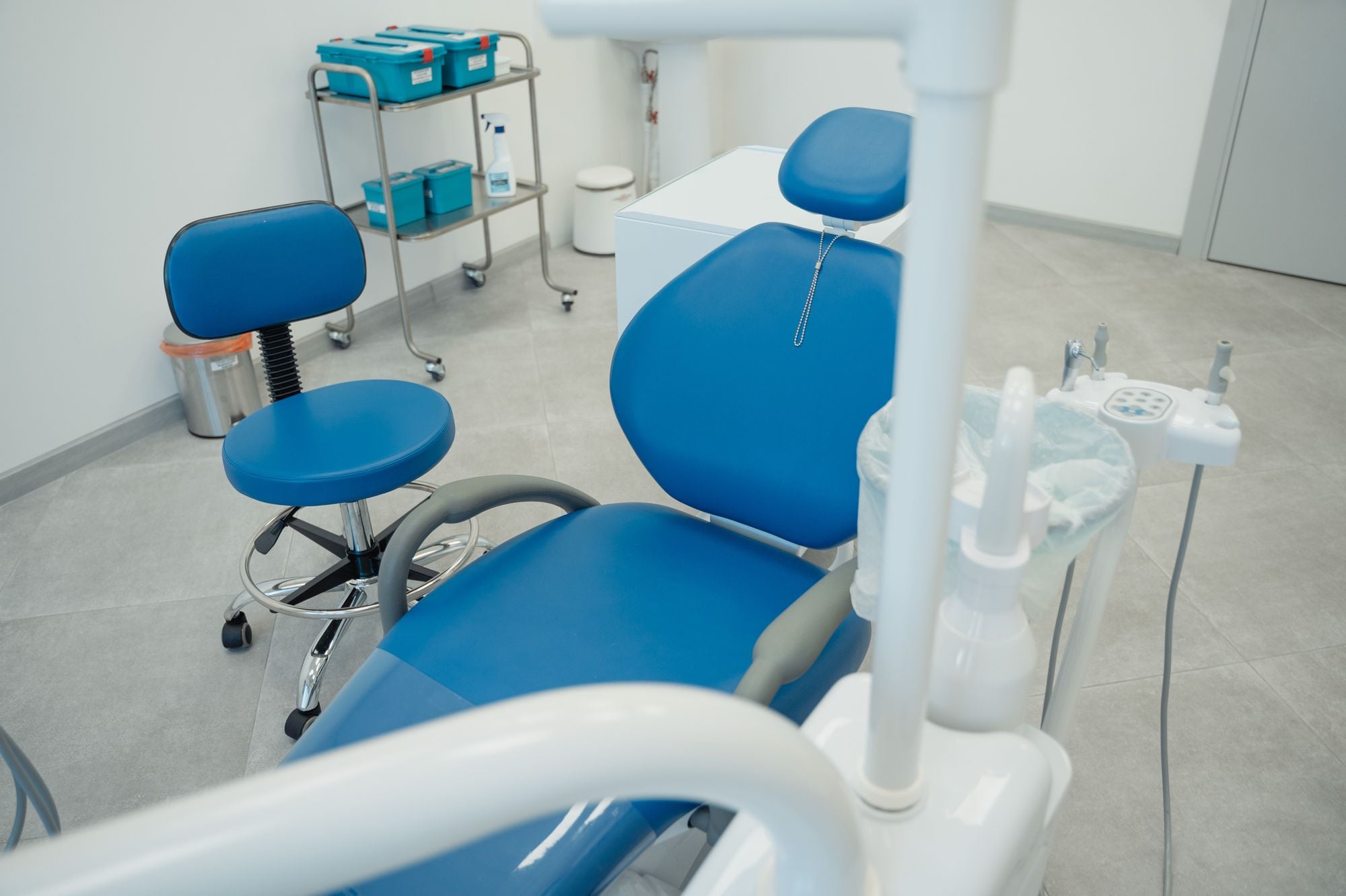 Dental operatory with a blue patient chair, delivery unit and white cabinets