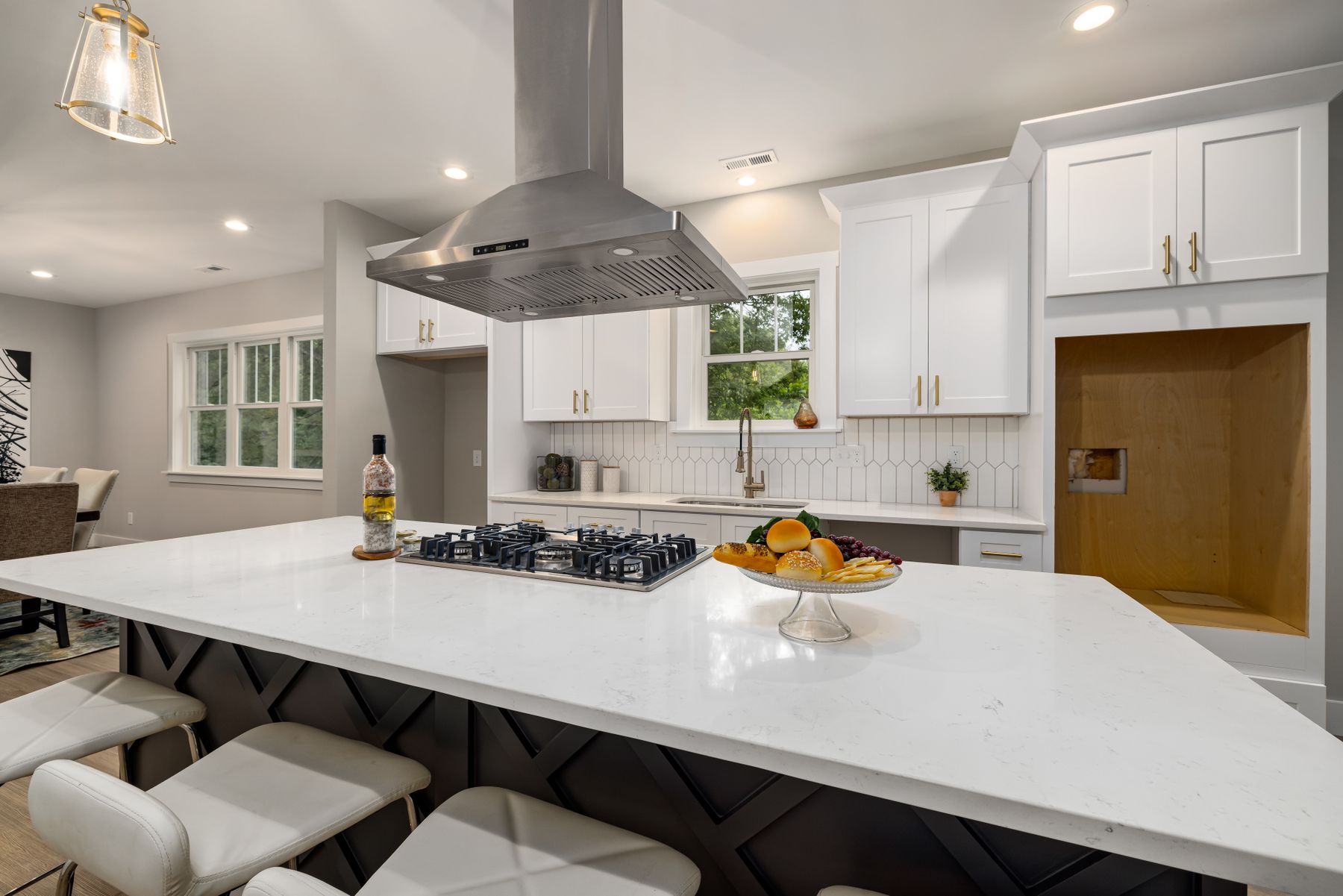 Gas cooktop set into a white island beneath a stainless range hood