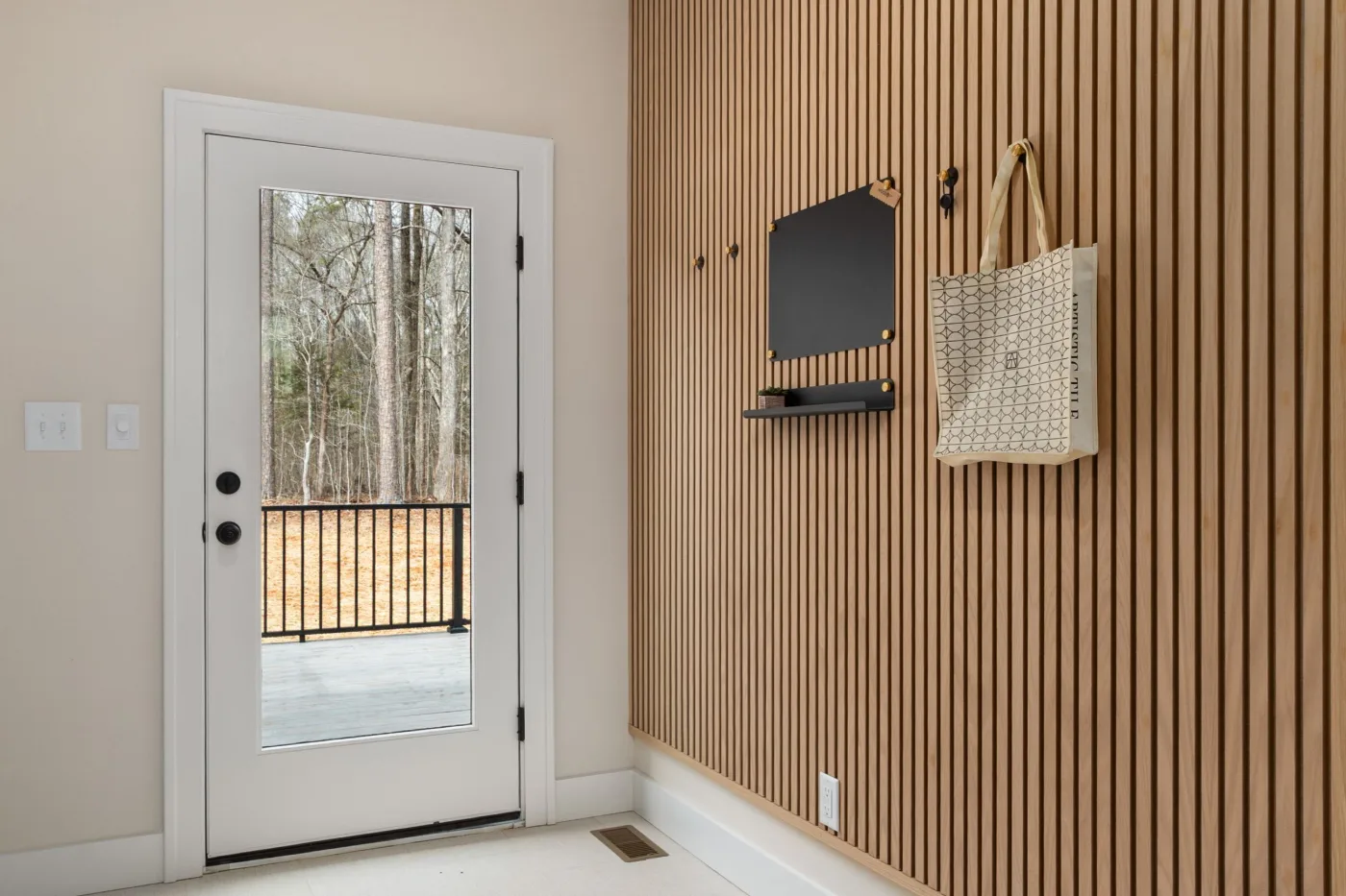 White exterior door with a half glass panel next to a slatted wood accent wall