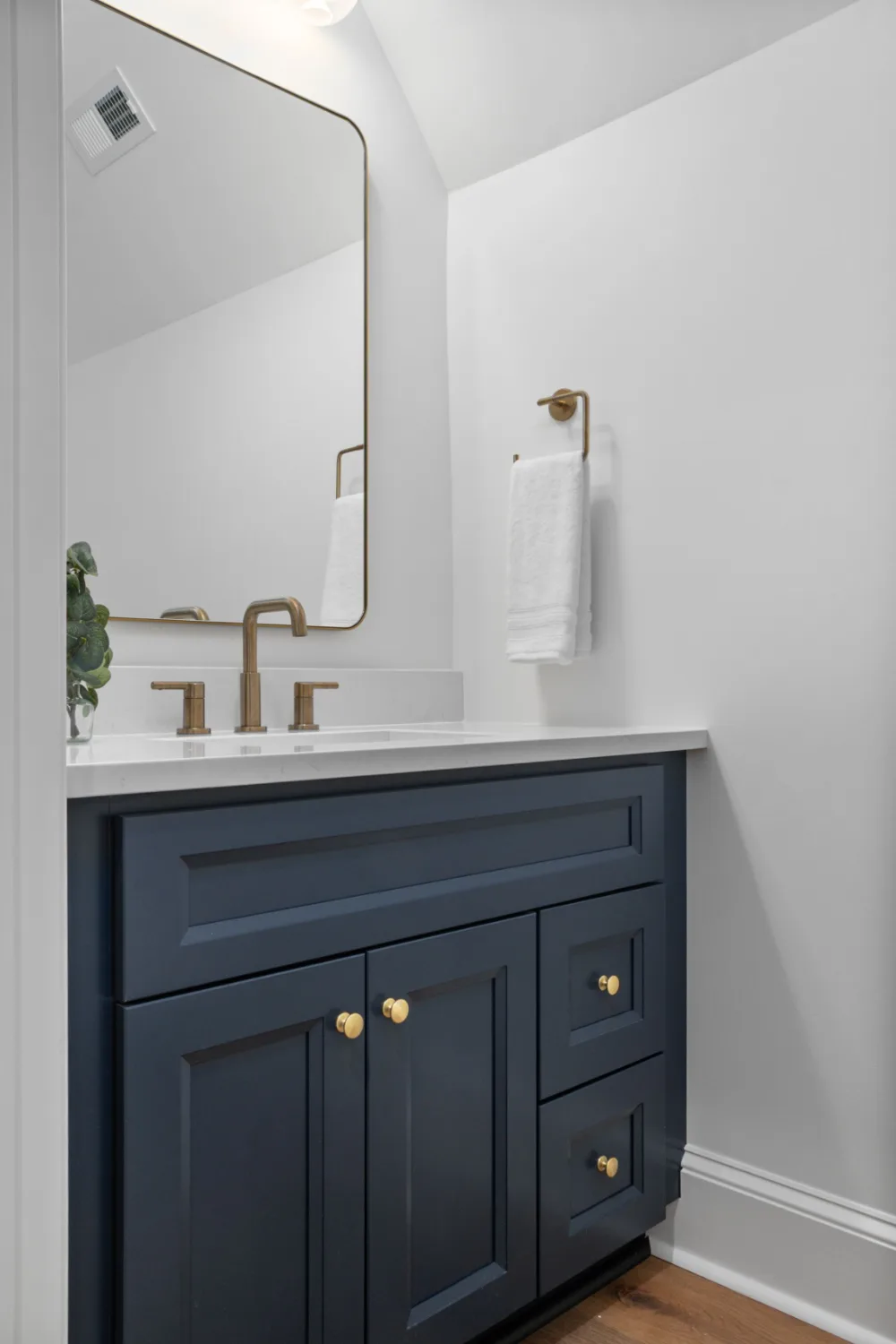 Navy bathroom vanity with a brass faucet and a white countertop