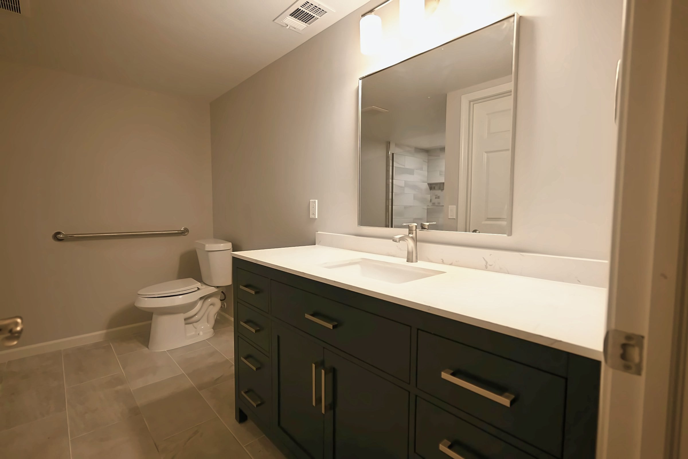 Remodeled Plymouth basement bathroom with a green vanity and a walk-in shower