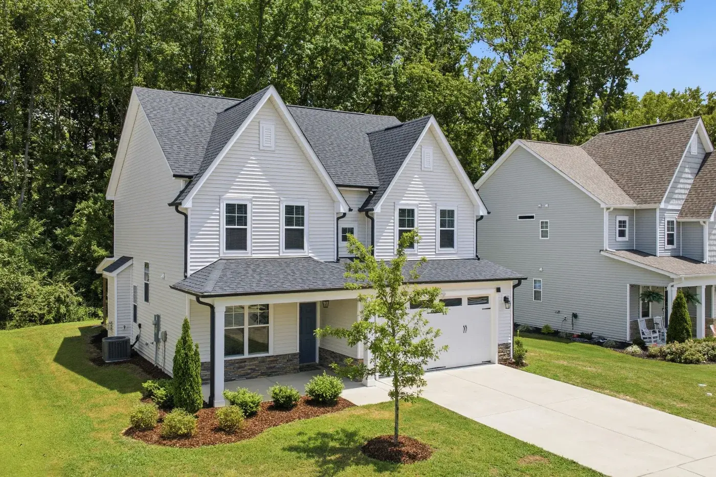 Two-story house with gray siding, a front porch and a landscaped lawn