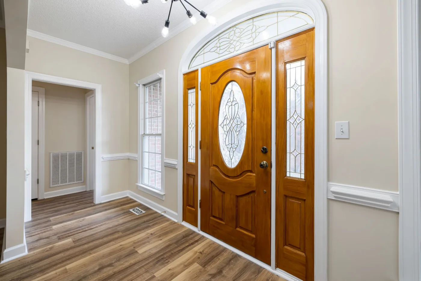 Wood entry door with an oval decorative glass insert, a matching sidelight and a transom