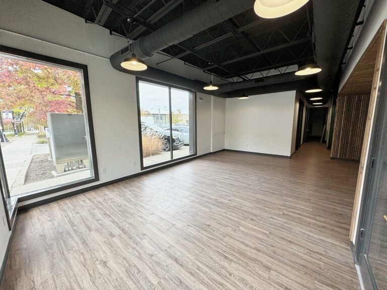 Finished open office in a Saline commercial build-out with tall street windows, an open black ceiling and wood-look plank floors