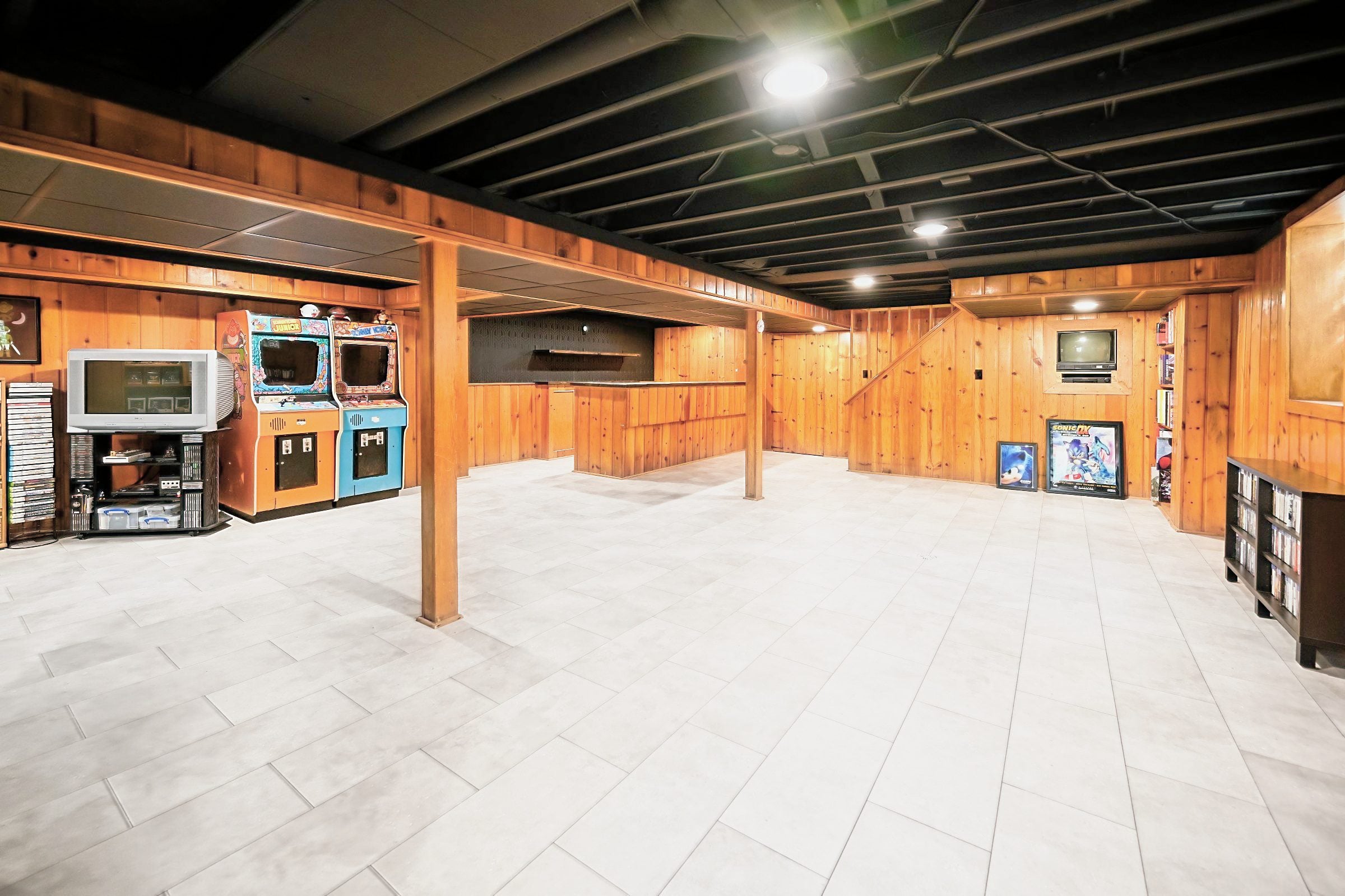 Finished basement game room in Ypsilanti with knotty pine walls and a black ceiling
