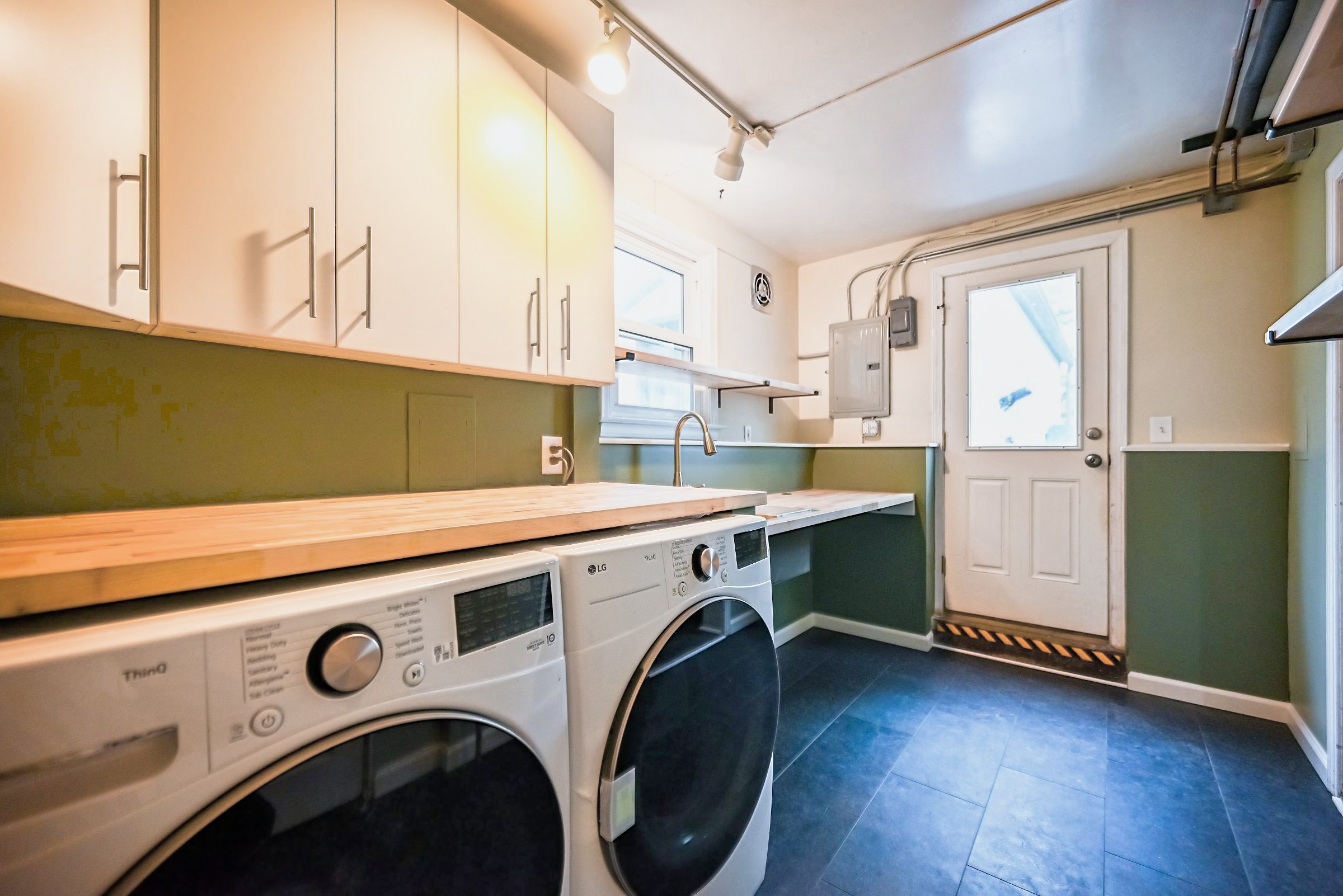 Remodeled Ypsilanti laundry and mudroom with birch butcher block counters, white cabinets and green walls