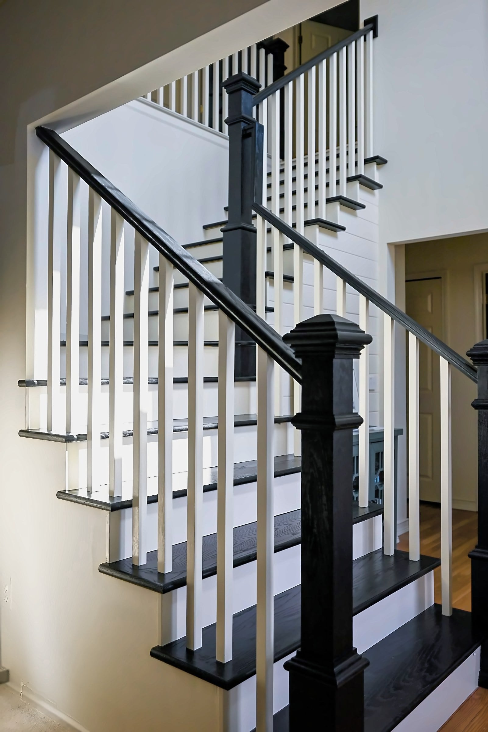 Rebuilt staircase in an Ypsilanti home with black oak treads, cream risers, white balusters and black newel posts